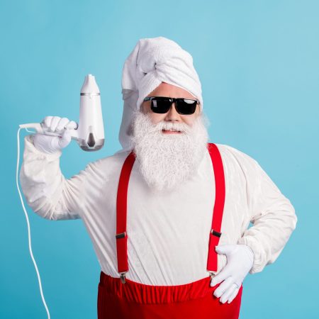 Photo of retired old fat man grey beard hold hair dryer get out shower, ready make stylish hairdo wear santa costume towel turban suspender sunglass isolated blue color background